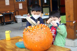 two boys driving golf tees into a pumpkin at Hands On Children's Museum's Boos Bash