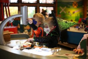 two kids in halloween costumes doing an activity at Hands On Children's Museum