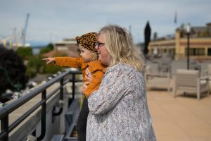 a woman holding a child looking over a balcony at Harbor Heights 55+ apartments in Olympia