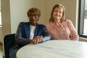 two women sitting at a round table smiling