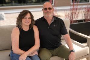 Scott and Laurie sitting on an outdoor patio couch at Harbor Heights in Olympia