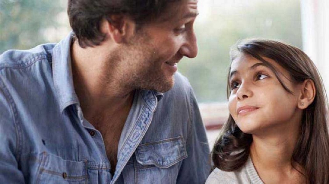 close up of a dad smiling at his daughter who is looking up at him