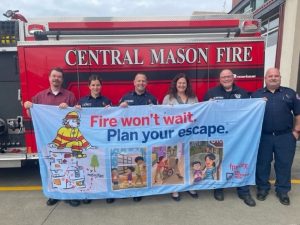 Melanie Bakala of State Farm (center) joins with local firefighters to urge you to plan and practice your fire evacuation route at your home.