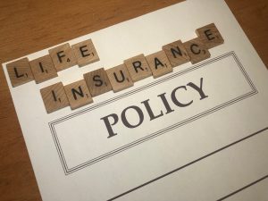 scramble letters spelling out 'life insurance' on a piece of paper that says 'policy'