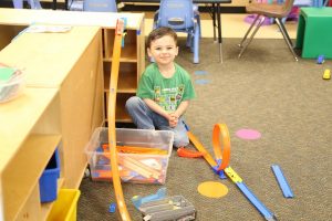 a child playing on the floor with a plastic racetrack