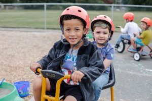 two boys with helmets on riding a tandem bike