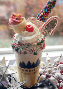 fancy blended coffee drink with whipped cream, a candy cane and a mini cupcake on top at Northwest Grind Coffee