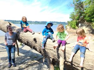 kids playing on a huge log on a beach