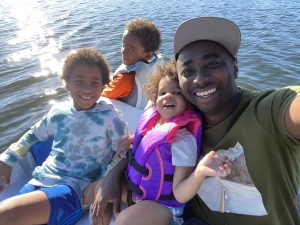 Parfait Bassalé on a body of water with his three kids