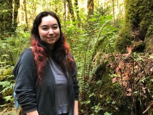 Marie Kelley standing next to mushrooms growing at The Evergreen State College campus