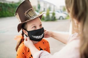 a kid in a halloween costume with a scary face mask