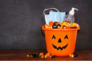 plastic pumpkin treat bag full of treats, as well as face masks and hand sanitizer