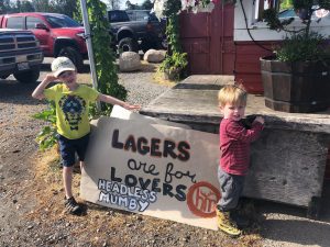 Headless Mumby Brewing in Olympia patio with a banner that says 'Lagers are for lovers' with two kids standing by it