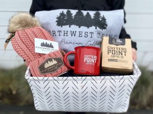 a basket with a coffee mug, coffee, beaning and a hoodie all with Northwest Grind logo on them