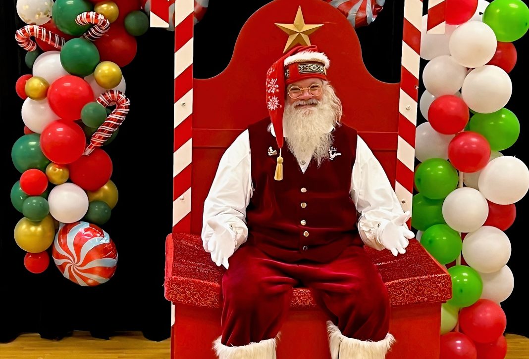santa sitting in a fancy throne with a balloon arch behind him in Lacey