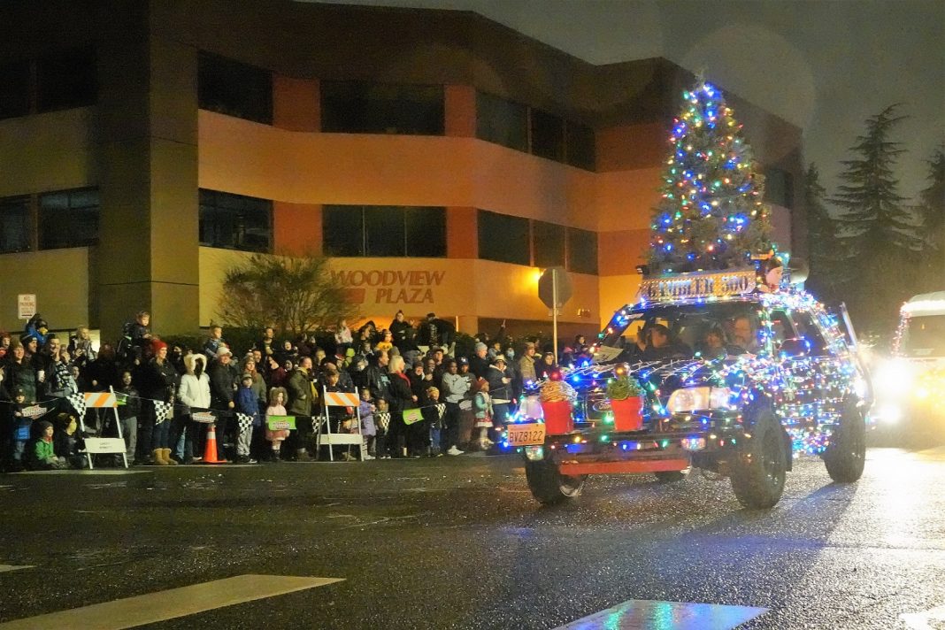 car all decked out in lights with a Christmas tree on top in a parade in the City of Lacey