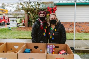 two women taking food donations the Tumwater Tree Lighting Festival