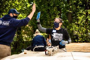 two people working on a house, high-fiving each other, for South Puget Sound Habitat for Humanity