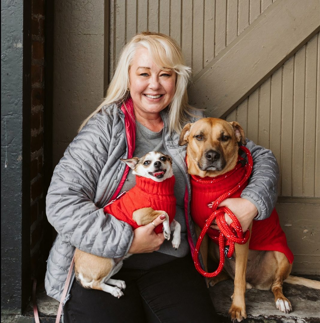 Heidi Retzlaff hugging a small and large dog in red sweaters
