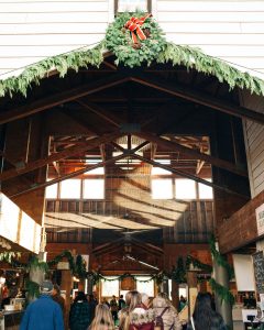 people shopping the Olympia Farmers Market building with shoppers and a wreath and swag on top