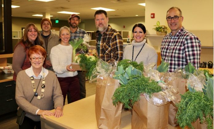 Mayor Andy Ryder and wife Becci Ryder (center) show off the contents of their Farmshare. (L-R) Marilyn Sitaker, Tina Sharp, Casey McCrone, Stephen Bramwell (behind Becci and Andy), Jeni Shaefer, and interim City Manager Rick Walk.