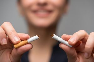 woman smiling while breaking a cigarette in half