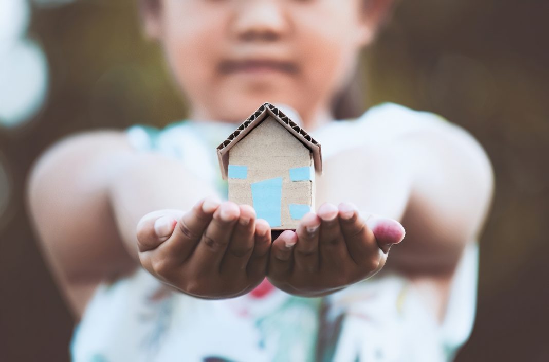 child holding a tiny home in both of her outstretched hands