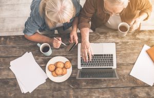 senior citizens sitting at a table with a laptop and coffee