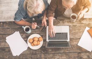 senior citizens sitting at a table  with a laptop and coffee