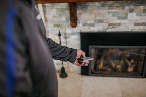person pointing a remote at an electric fireplace