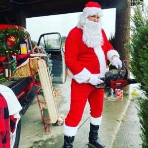 Santa with a chainsaw posing by a Christmas Tree at Lincoln Creek Lumber
