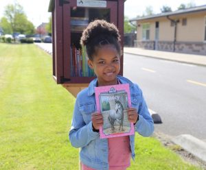 little girl with a book by a Little Free Library at a North Thurston Elementary School