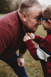 dad and young son staring into each other eyes with forward's touching - kid has hands on dad's collar