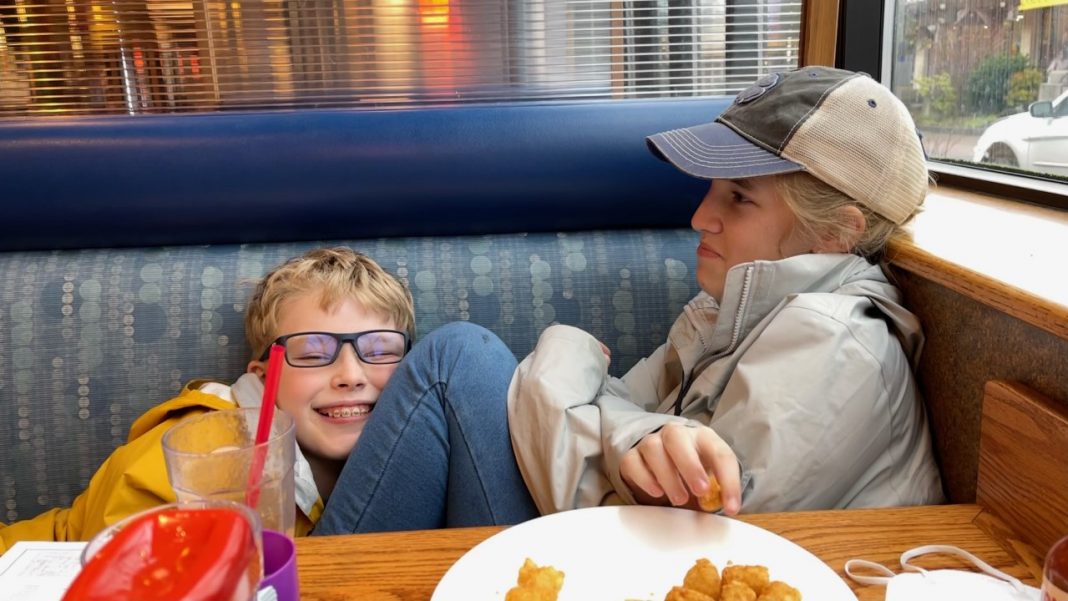 two kids in a diner booth, laughing