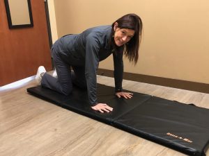 Dr. Jennifer Penrose on all fours on a mat, demonstrating how to get back up after a fall