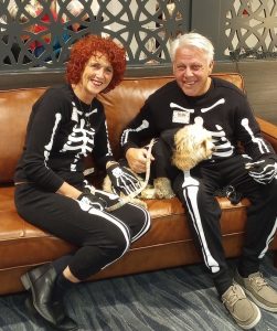 Fred and Debbie Paparelli dressed in skeleton costumes with their dog all sitting on a couch at Harbor Heights in Olympia