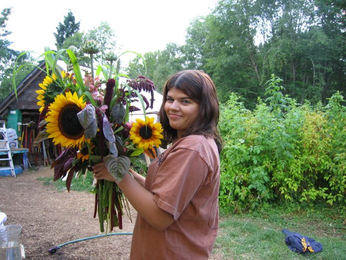 Selena Rodocker in summer 2008 holding sunflowers in a field