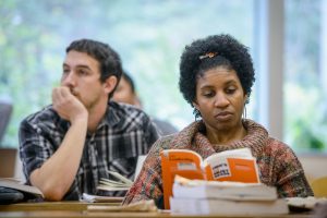 college students reading books at a long table