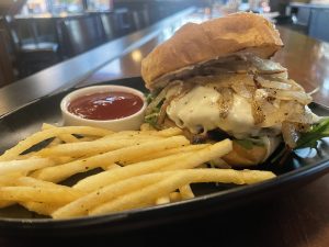 Cynara's Happy Hour Grilled Onion, Cheese Burger with fries on a table