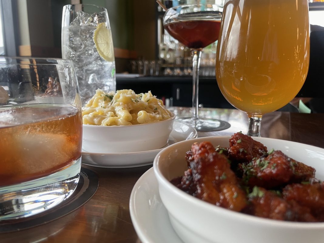 mac-and-cheese, pork belly candy, wine and cocktails on a table at Cynara