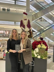 Fleurae Floral Design owners Iana Franks and Amber Geiger standing in front of their santa made of flowers with their reward