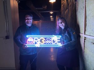Legends Arcade owners Patrick and Christina Costelo hold the neon sign for their new business