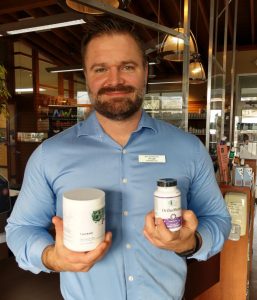 Pharmacist Ryan Martin at NW Remedies holding two supplement jars in his hands and smiling at the camera