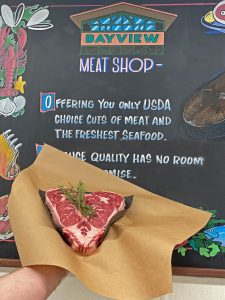 fresh, heart-shaped steak on brown paper with herbs on top