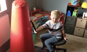 child hitting a punching bag with a stick at Olympia Therapy