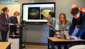 Pope John Paul II High School students working on a presentation on a large screen