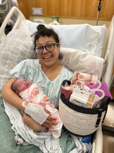 mother with newborn daughter in bed at Providence hospital with a gift basket.