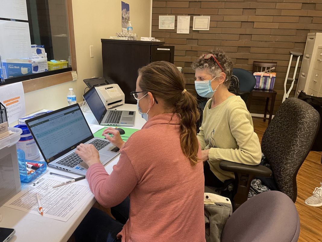 two people sitting behind the counter at computers at The Olympia Free Clinic