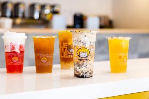 various bubble teas in different colors - red and white, yellow, orange, brown and white - on a counter