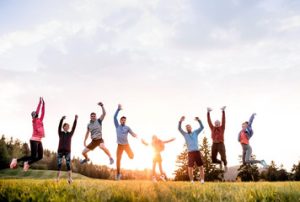a group of senior citizens jumping into the air in a field at sunset